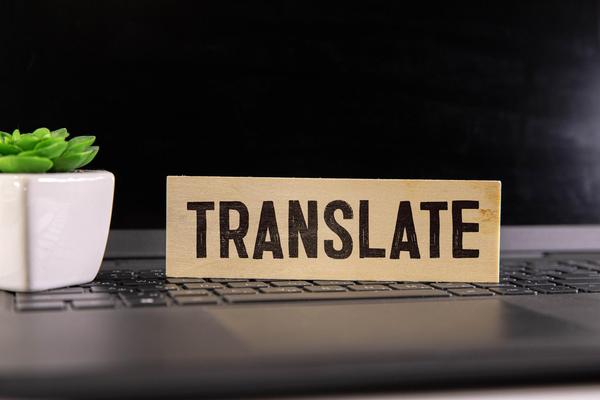 Wooden block with the word “Translate” on a laptop keyboard, symbolising the need for clear invoice communication.
